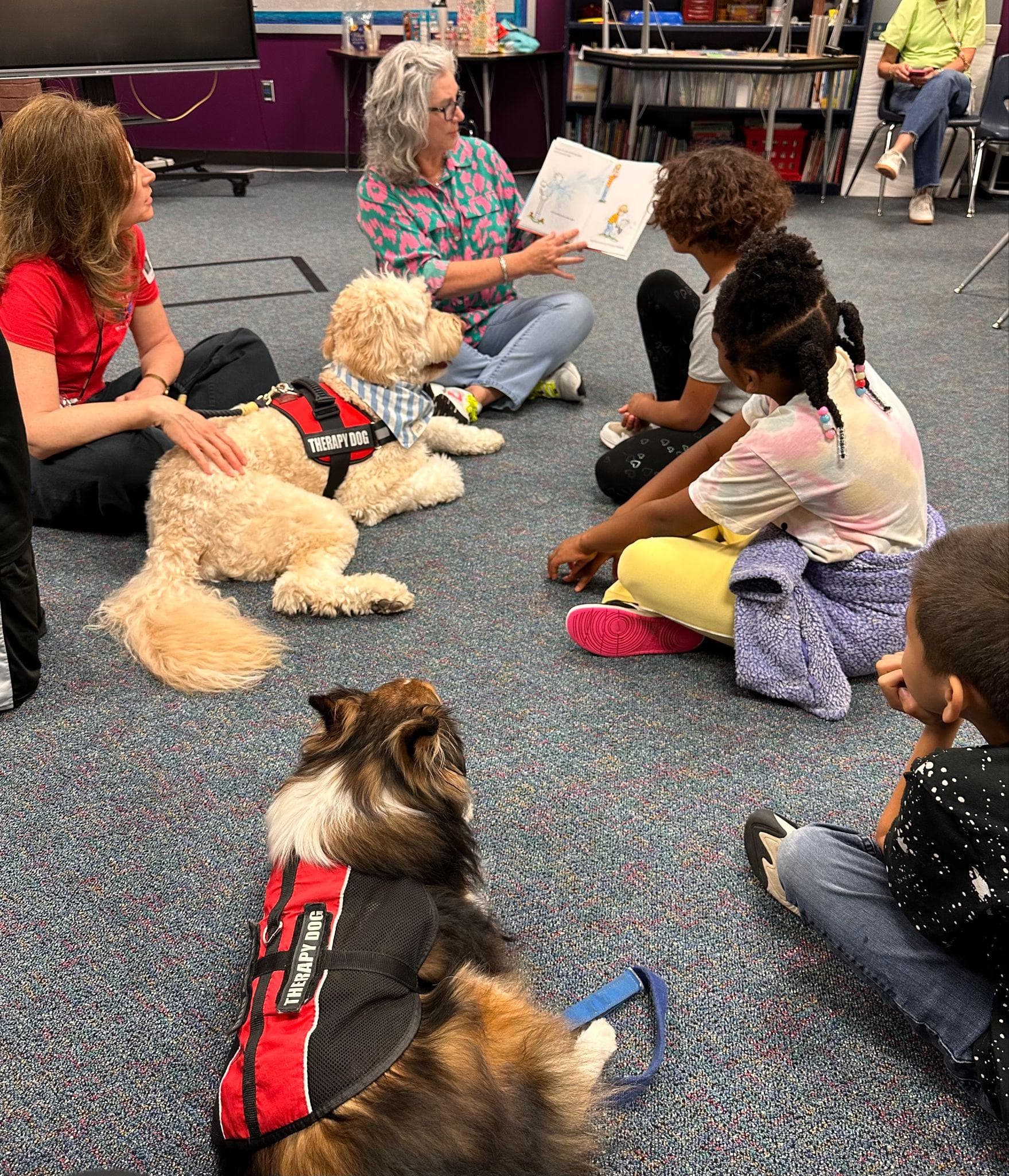 Students reading with Angel Paws therapy dogs in a classroom